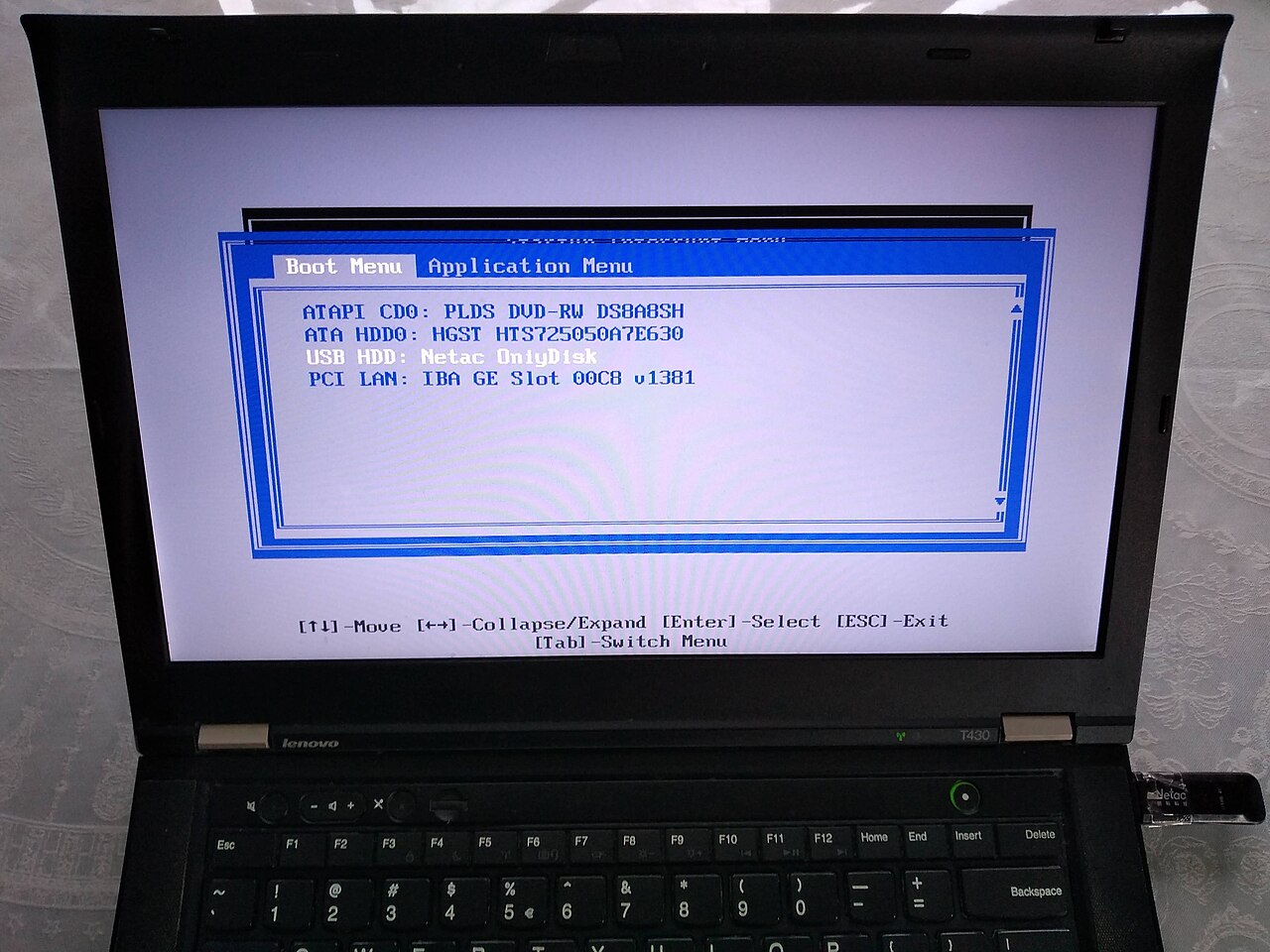 A Lenovo ThinkPad T430 showing its F12 one-time Boot Menu with four entries: ATAPI CD0 DVD-RW drive, ATA HDD0 internal hard disk, USB HDD Netac OnlyDisk, and PCI LAN network boot, with the USB stick plugged into the laptop's side port